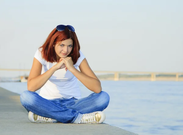 Jovem mulher sentada perto do rio no dia de verão — Fotografia de Stock