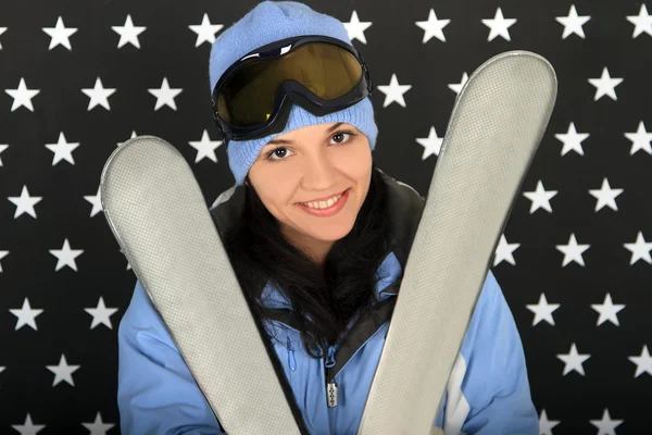 Счастливая девушка с лыжами в зимней спортивной одежде — стоковое фото