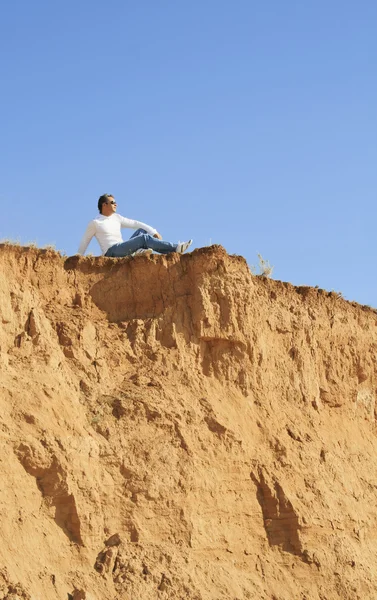 Junger kaukasischer Mann sitzt allein auf dem Felsen — Stockfoto