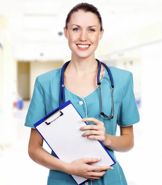 Médico en el pasillo del hospital sujetando el portapapeles y sonriéndote —  Fotos de Stock