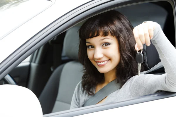 Pretty female driver in a white car showing the car key — Stock Photo, Image