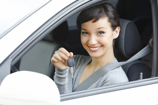 Красивая женщина-водитель в белой машине показывает ключ от машины — стоковое фото