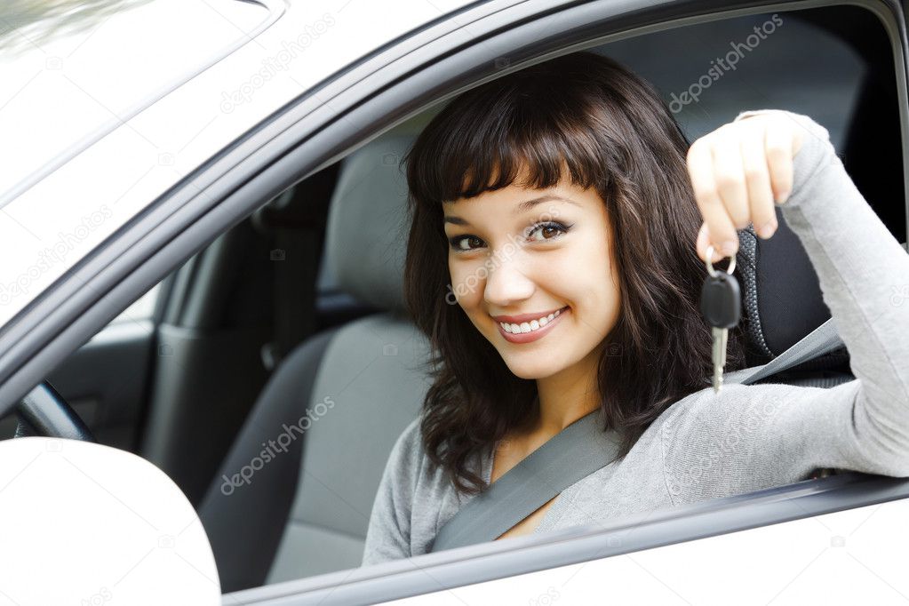 Pretty female driver in a white car showing the car key