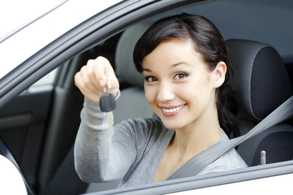 Motorista muito feminino em um carro branco mostrando a chave do carro . — Fotografia de Stock