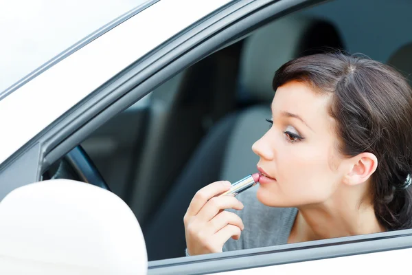 Jovem morena aplicando maquiagem enquanto no carro — Fotografia de Stock