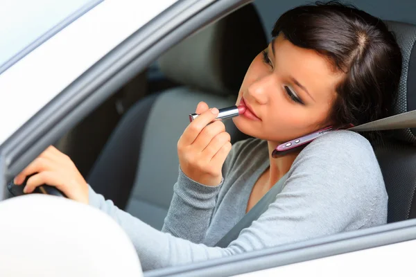 Female driver talking by mobile telephone and doing make-up. — Stock Photo, Image