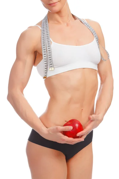 Muscular woman with apple and tape measure — Stock Photo, Image