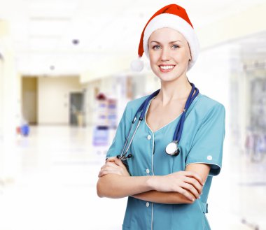 Smiling female medical doctor wearing red hat in a hall of a hos clipart