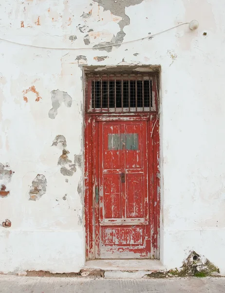 Old red door with bars on the white building. Background. — Stock Photo, Image