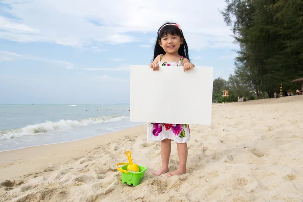 Malé dítě dívka drží bílou tabuli na pláži — Stock fotografie
