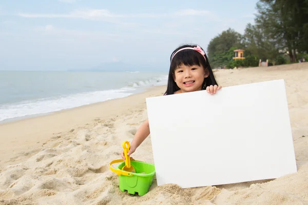Malé dítě dívka drží bílou tabuli na pláži — Stock fotografie