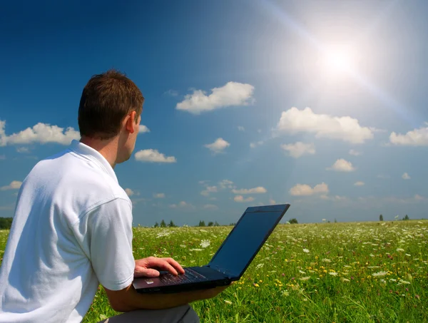 Uomo con laptop in campo verde Foto Stock Royalty Free