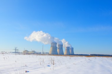 Nuclear power plant on blue winter sky background and snow cover