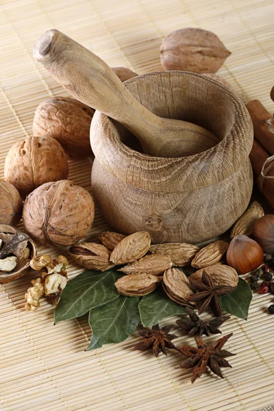 Wooden mortar and pestle with spices and nuts — Stock Photo, Image