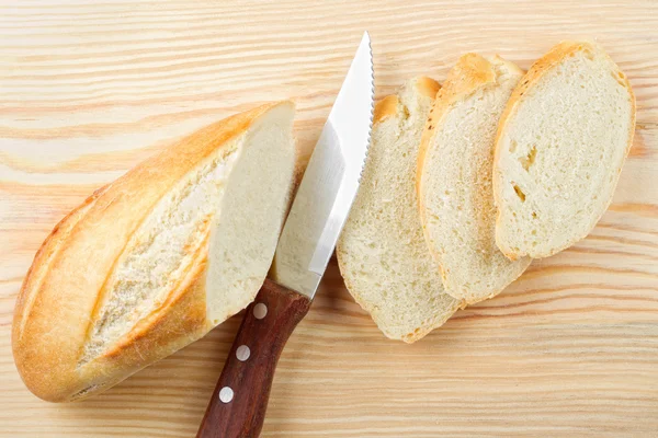 Freshly baked baguette sliced on wooden board — Stock Photo, Image