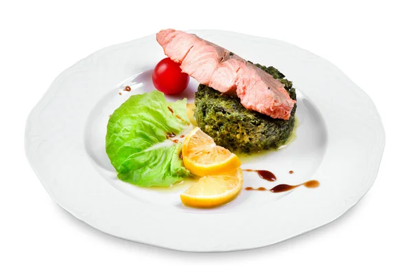 Salmon with spinach garnish, cherry tomato, lemon slices on a pl — Stock Photo, Image