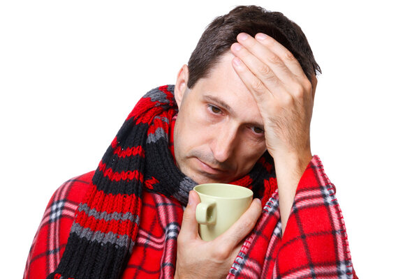 Cold man with flu wrapped in a warm blanket, holding a mug