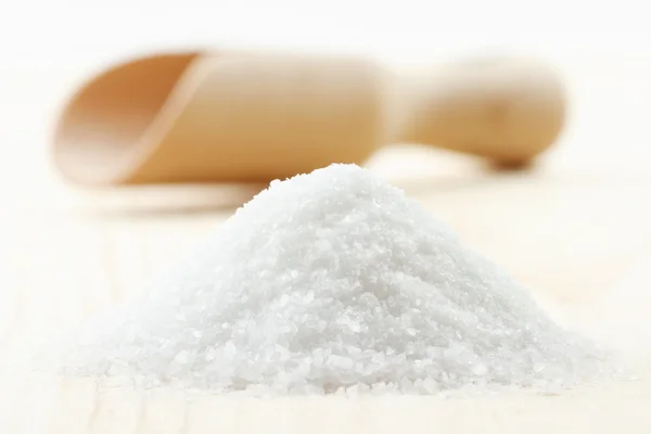 Pile of sea salt on wooden board, scoop on background — Stock Photo, Image