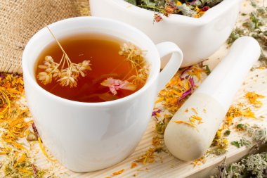 Cup of healthy tea, mortar and pestle with healing herbs clipart