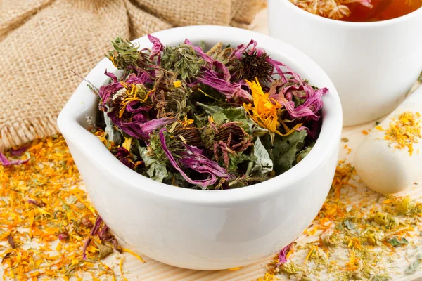 Argamassa e pilão com ervas curativas, xícara de chá saudável em madeira — Fotografia de Stock