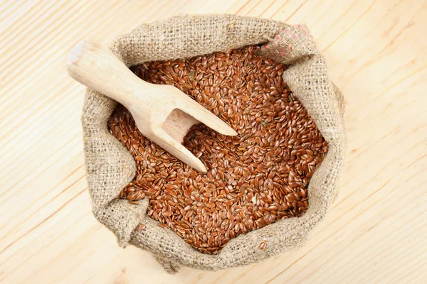 Linseed, flax seeds with wooden scoop in sack — Stock Photo, Image