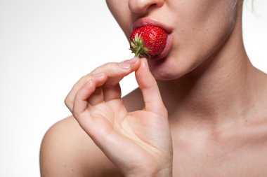 Young woman biting strawberry isolated on white