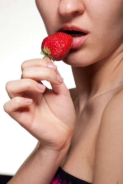 Młoda kobieta gryzienie truskawki na białym tle — Zdjęcie stockowe