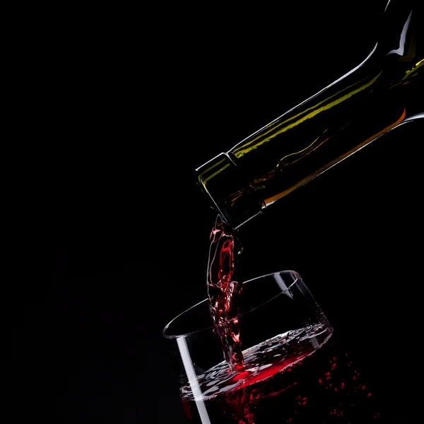 Красное вино наливается в бокал вина изолированы на черный — стоковое фото