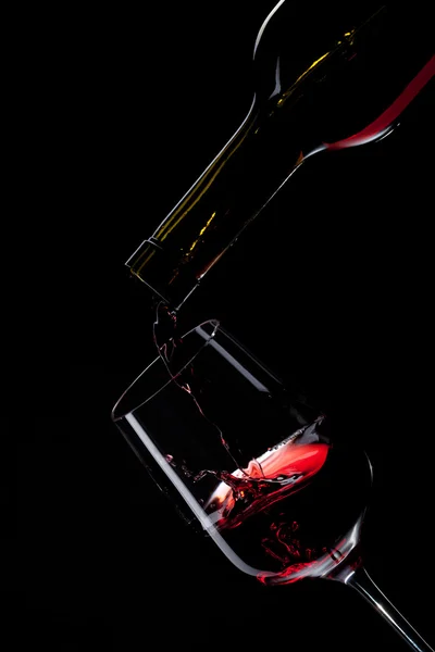 블랙에 고립 된 와인 글라스에 붓는 레드 와인 — 스톡 사진