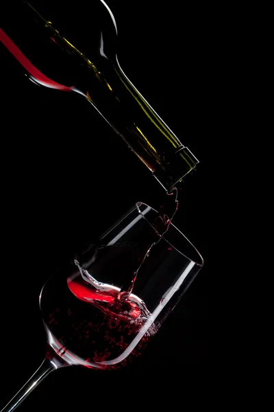 Rött vin hälla i glas vin isolerade på svart — Stockfoto