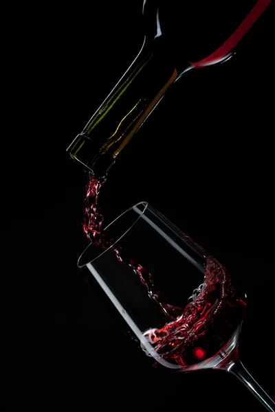 Red wine pouring into wine glass isolated on black — Stock Photo, Image