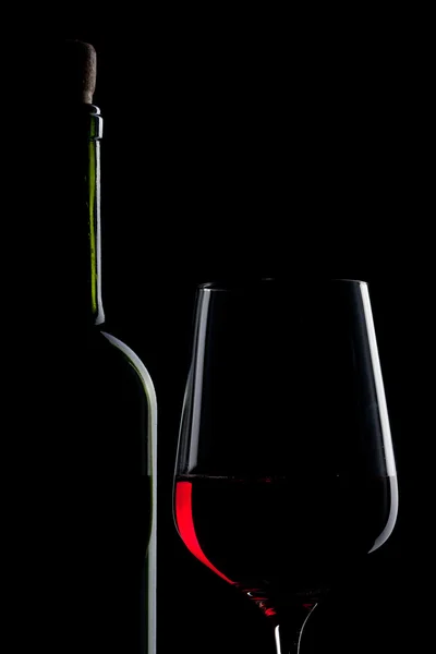 Czerwone wino w szkło i butelka na czarnym tle — Zdjęcie stockowe