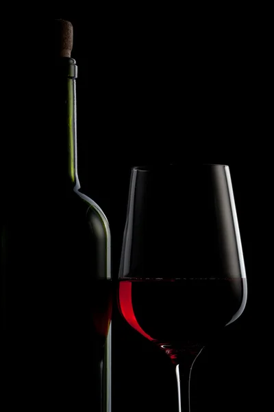 Rött vin i glas och flaska isolerade på svart — Stockfoto