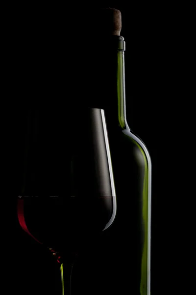 Rött vin i glas och flaska isolerade på svart — Stockfoto