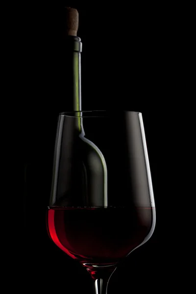 Красное вино в стакане и бутылка изолированы на черном — стоковое фото