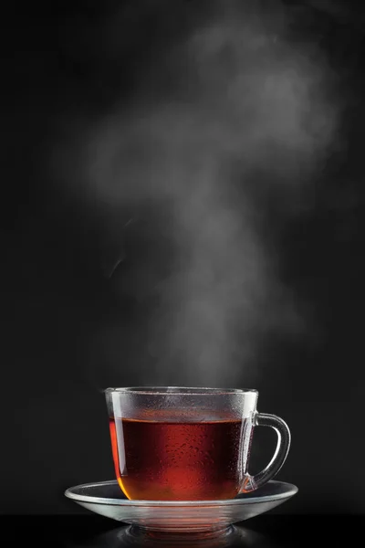 Xícara com chá quente e vapor em preto — Fotografia de Stock