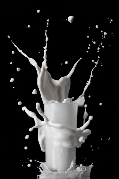 Mleko rozchlapać szkło na białym tle na czarnym tle — Zdjęcie stockowe