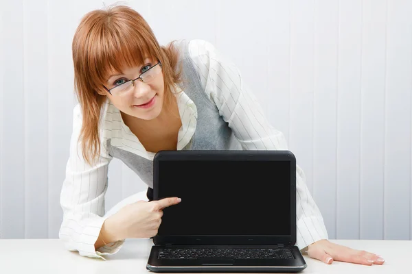 Dívka s brýlemi ukazuje prstem na laptop — Stock fotografie