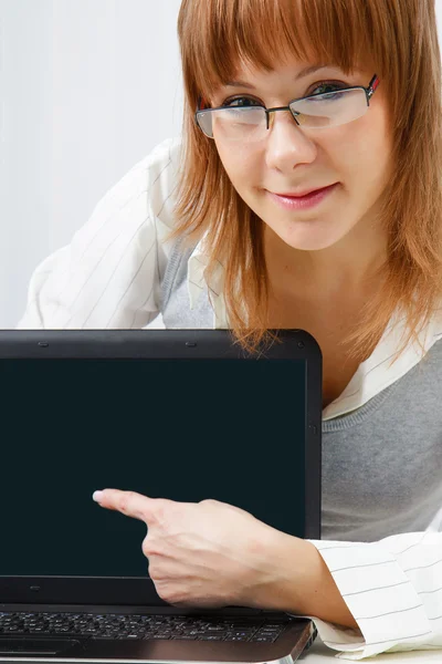 Chica con gafas muestra un dedo en un ordenador portátil —  Fotos de Stock