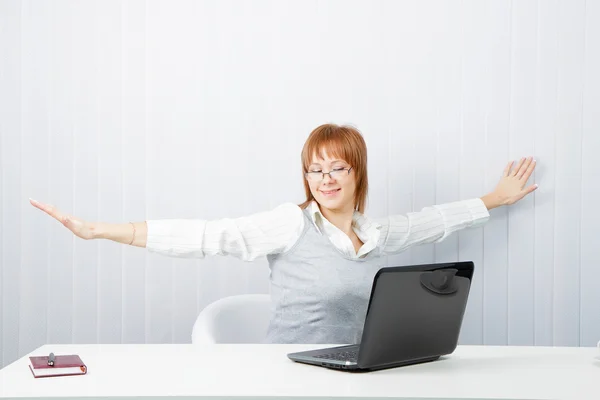 Menina com um laptop se estende no local de trabalho — Fotografia de Stock