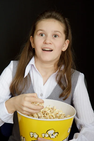 Chica sorprendida con palomitas de maíz sobre un fondo negro — Foto de Stock