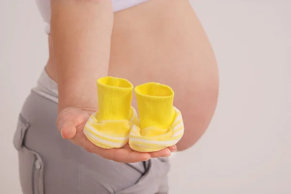 Mulher grávida segurando botas amarelas — Fotografia de Stock