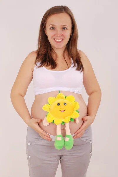 Mulher grávida colocou o brinquedo no estômago — Fotografia de Stock