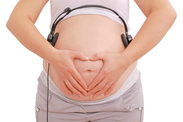 Zwangere vrouw met hoofdtelefoon op haar buik — Stockfoto