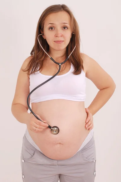 Беременная женщина слушает брюшную полость стектоскопа — стоковое фото