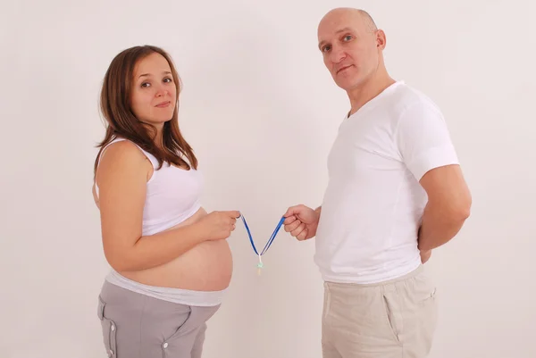 Pregnant woman and her husband in his hands Dummies — Stock Photo, Image