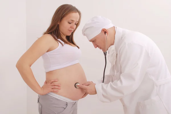 Der Arzt hält eine Spritze in der Nähe des Unterleibs einer schwangeren Frau — Stockfoto