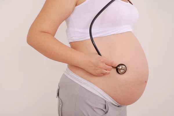 Беременная женщина слушает брюшную полость стектоскопа — стоковое фото