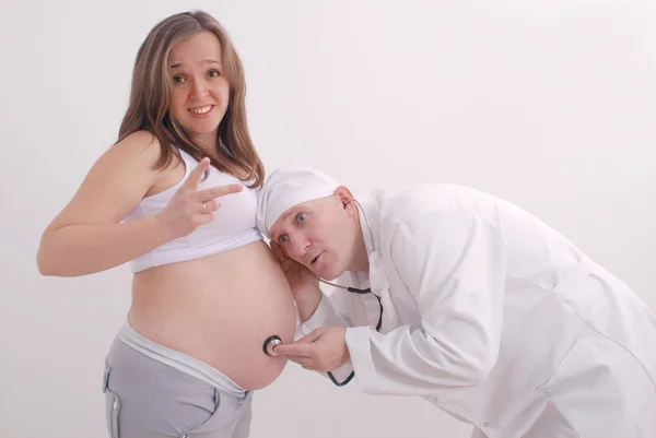 The doctor listens to the abdomen of pregnant woman
