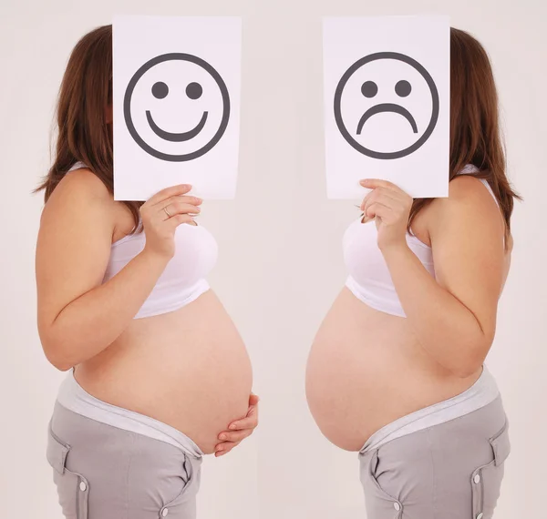 Těhotná žena se mračil a usmívající se tvář kartu. — Stock fotografie